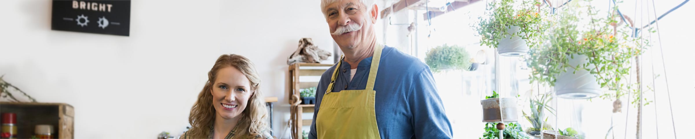 Older gardening business owner posing with young worker