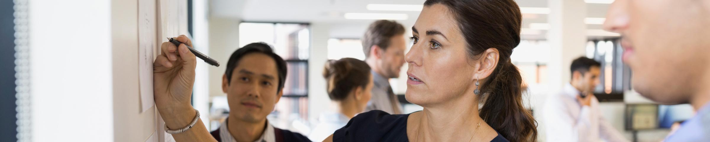 Female professional reviewing a plan on a white board